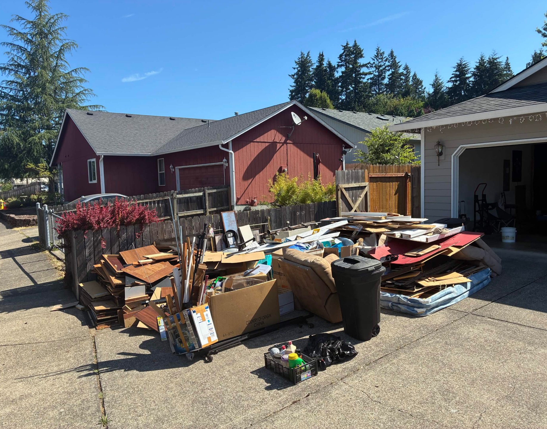 Driveway piled with furniture, cardboard, and debris before Haul Away junk removal